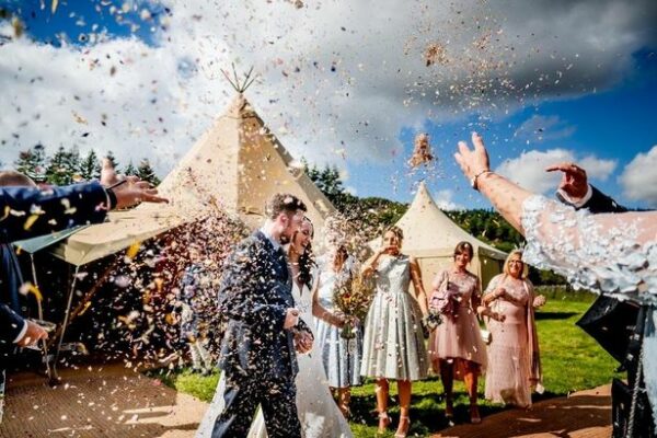 Summer Tent Tipi Wedding Wedding Guests Throwing Confetti over Newlyweds at Outdoor Wedding