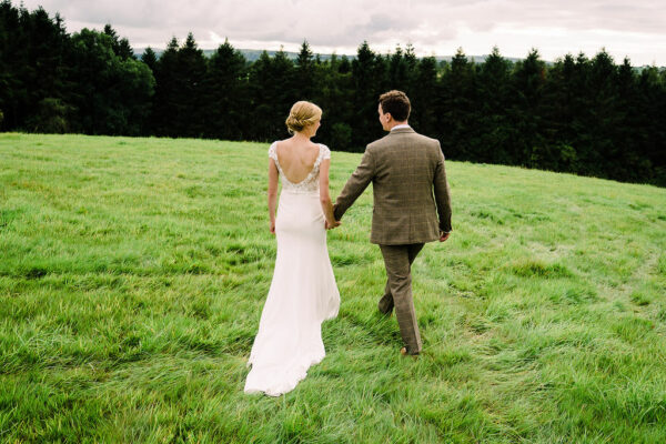Bride and Groom Walk Through Field Hand in Hand - Fairytale Wedding