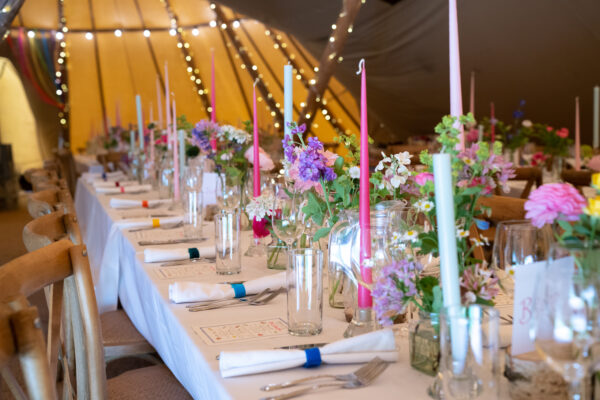 Colourful candles on long banqueting tables in a tipi