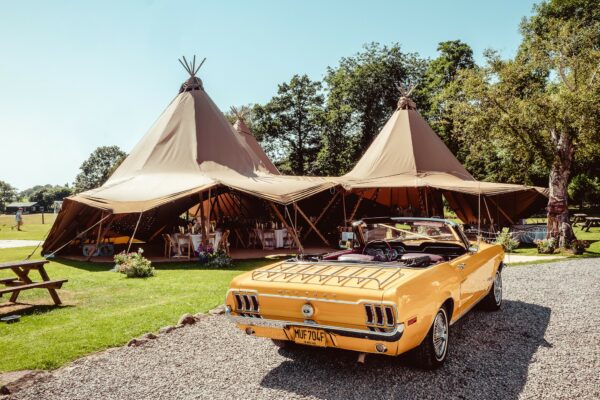 Summer Lake District Tipi wedding with raised sides and fancy yellow sports car