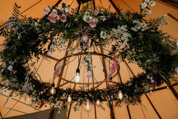 Tipi flower inspiration - Beautiful Tipi wedding decorations Edison chandelier covered in foliage. Created by wedding florist Winter and the Willows