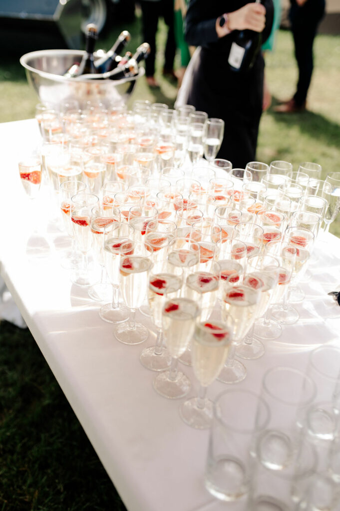 Welcome drinks table with glasses of champagne and raspberries. Tipi Wedding welcome table under a Nimbus Tipi