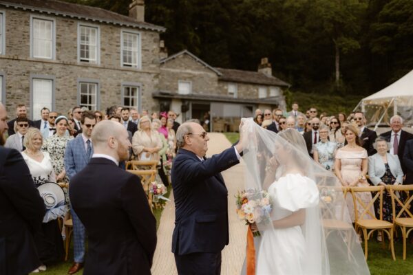 Father of the bride, giving her away. Outdoor Sailcloth Marquee Wedding Ceremony in the Lake District