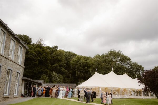Outdoor Wedding in the Lake District, guests waiting to be welcomed into the Sailcloth Marquee for the wedding breakfast
