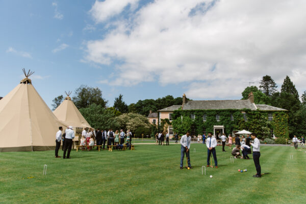 Tipi Wedding at Low House, Armathwaite on the perfect lawn, with wedding guests playing croquet